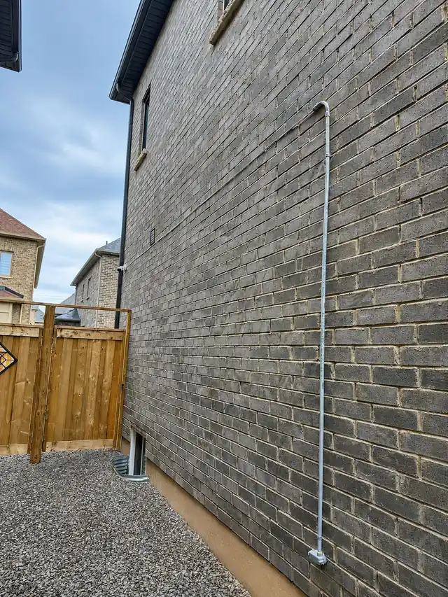 Camera cable run in straight conduit along a brick wall